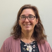 Photo of Rebecca Haug wearing pink sweater, flower shirt and glasses
